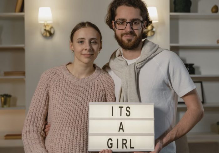 Happy couple inside home reveals baby's gender with a charming lightbox sign.