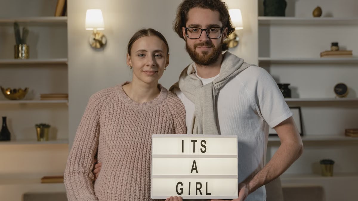 Happy couple inside home reveals baby's gender with a charming lightbox sign.